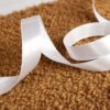 Ruban satin blanc uni déroulé sur un tissu bouclé
